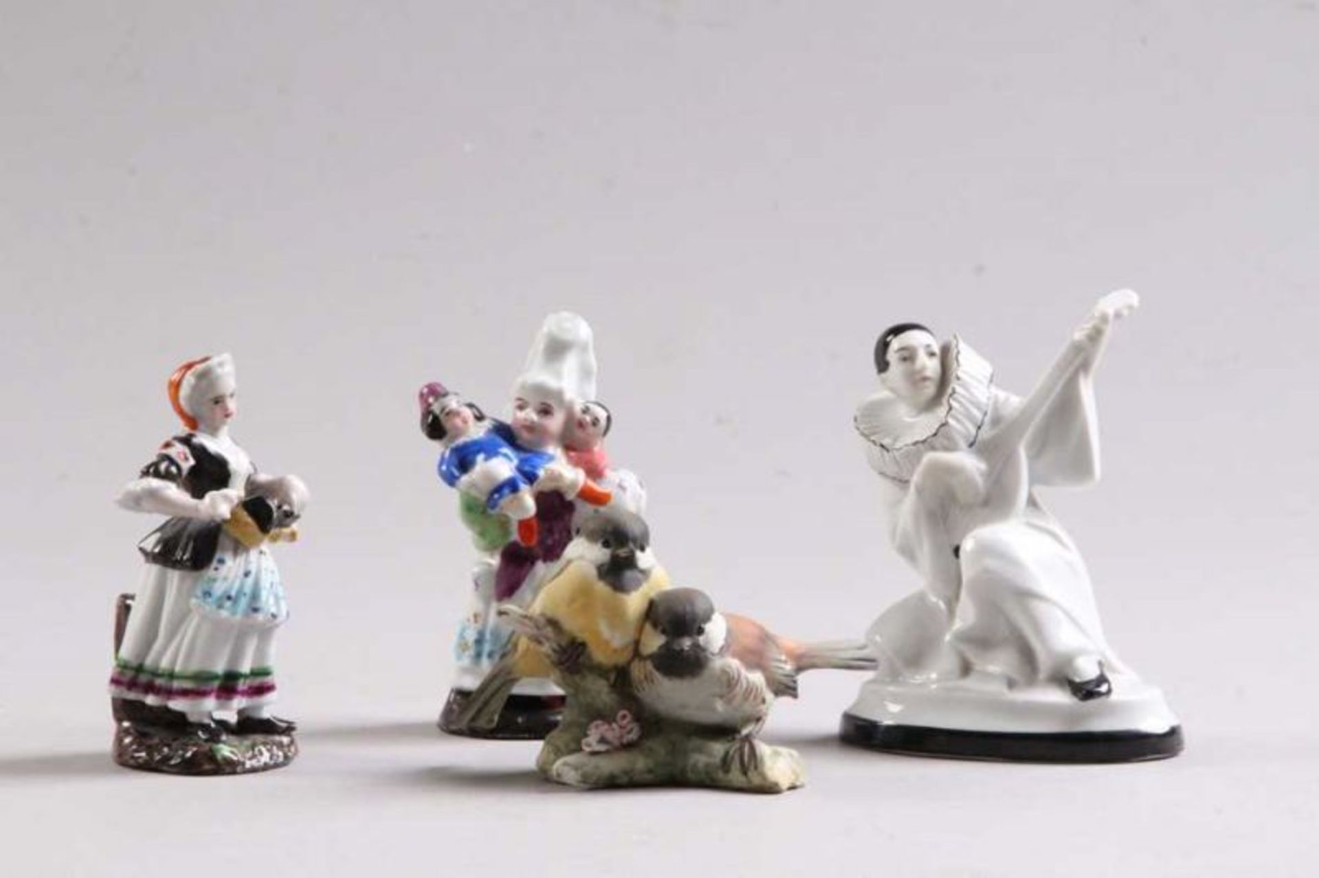 Vier Porzellanfiguren.19./20.Jh. Porzellan. Pierrot mit Laute, Dame mit Drehleier, Mutter mit zwei