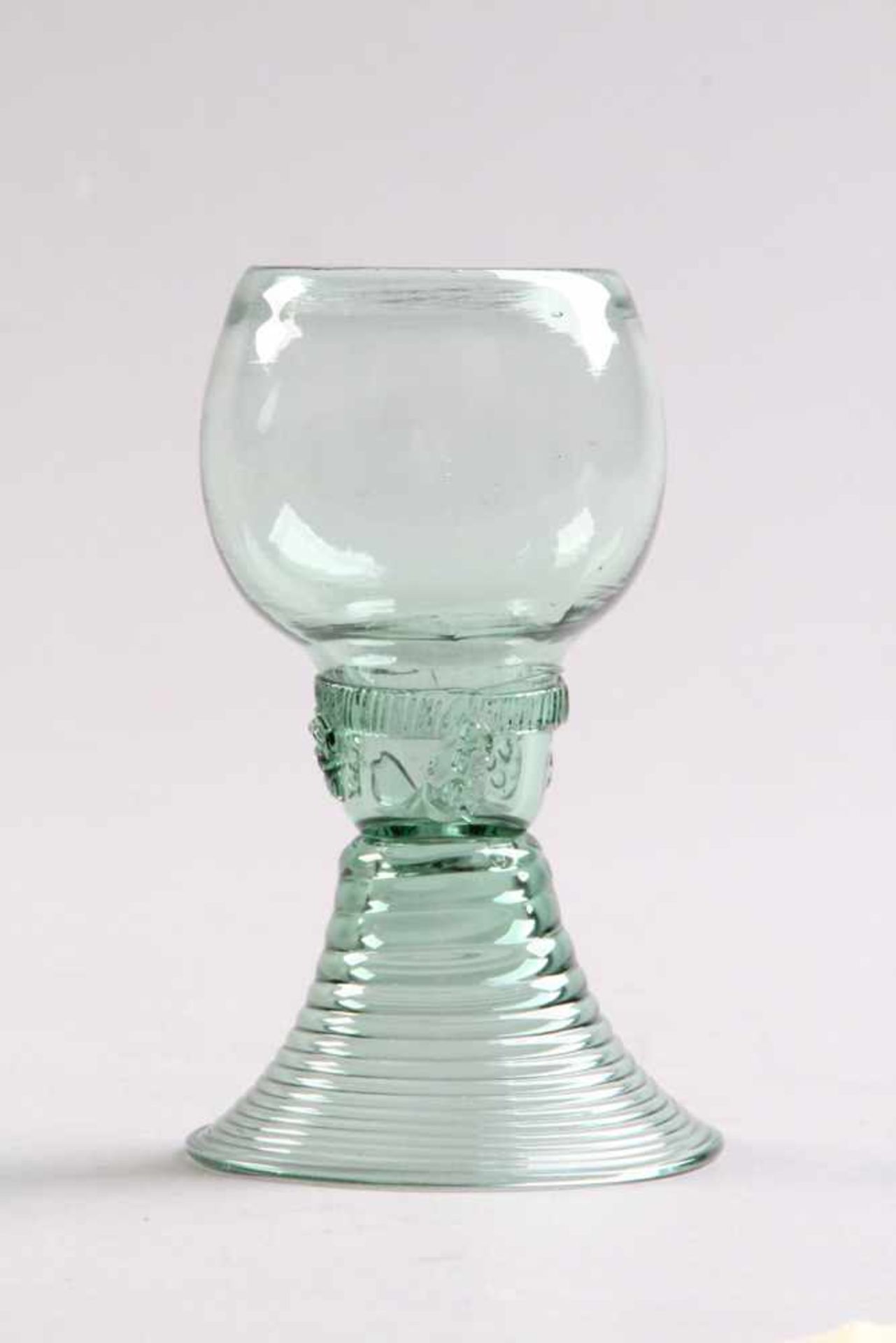 Römer.Um 1700. Grünliches Glas, gedrehter Hohlfuß, unterhalb der Kuppa aufgeschmolzenes Raupenband