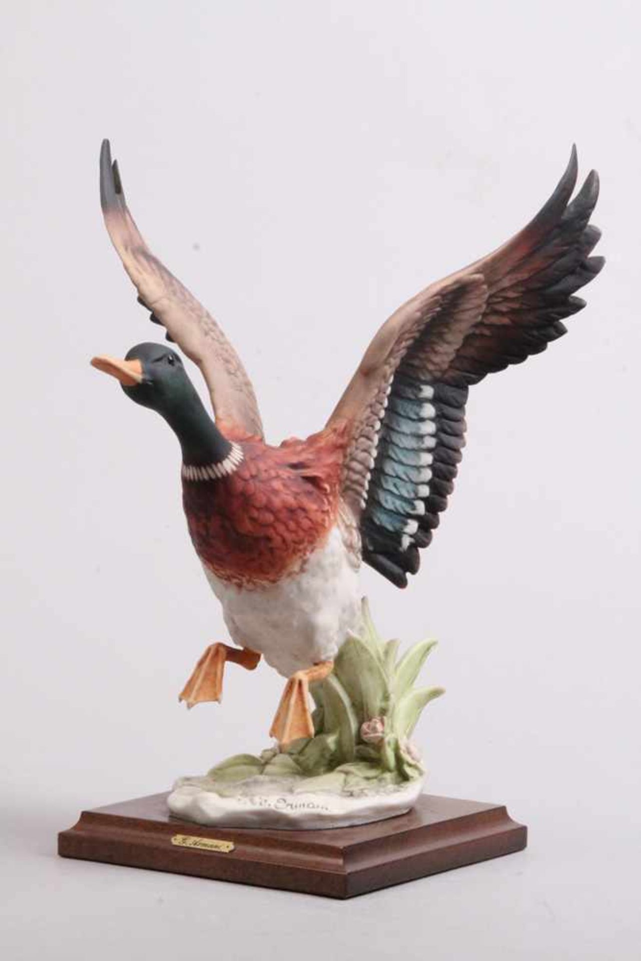 Porzellanfigur.Nach 1900. Unglasiert, naturalistisch bemalt. Landende Ente auf einem Schilfsockel,