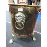 A vintage brass coal bin on animalistic feet and a wrought iron coal shovel