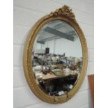 An oval gilt mirror with floral decoration