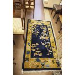 A 20TH CENTURY CHINESE WALL RUNNER, the navy ground decorated with gold border with floral motifs.