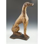 A GILT PLASTER MODEL OF A SEATED HOUND, 20th Century, on shaped plinth base, 74cm high.