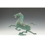 A CHINESE BRONZE MODEL OF A STRIDING HORSE, modelled in the Tang style and balanced on one foot.