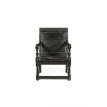 A BLACK STAINED PANELLED BACK OPEN ARMCHAIR, 17TH CENTURY, of large proportions with scrolled arms.