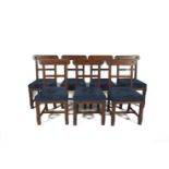 A SET OF SEVEN DINING CHAIRS with rail backs having carved rosettes on chamfered supports and