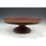 A 19TH CENTURY MAHOGANY CIRCULAR REVOLVING 'LAZY-SUSAN', with everted rim and raised on heavy turned
