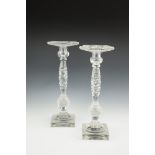 A PAIR OF 19TH CENTURY TALL FACET CUT GLASS CANDELSTICKS, raised on square lemon squeezer bases.