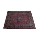 A SEMI-ANTIQUE TABRIZ STYLE WOOL RUG, the deep red ground with central medallion and foliate field