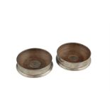 A PAIR OF MODERN SILVER CIRCULAR DECANTER COASTERS, London marks, with turned timber bases and