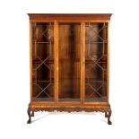 A GEORGIAN STYLE MAHOGANY TRIPLE DOOR DISPLAY CABINET, in the Chippendale taste with dentil