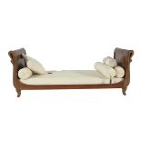 A GERMAN EARLY 19TH CENTURY WALNUT FRAME DAY BED, the double scroll ends formed as swan necks raised