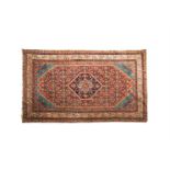 AN OLD TURKISH RED GROUND WOOL CARPET, the large centre field woven with a floral medallion,