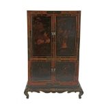 A CHINESE BLACK LACQUER CABINET, with twin panel doors above a twin panel door base decorated in red