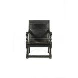 A BLACK STAINED PANELLED BACK OPEN ARMCHAIR, 17TH CENTURY, of large proportions with scrolled arms.