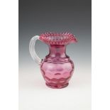 A LARGE VICTORIAN CRANBERRY GLASS JUG, with crimped rim and clear glass moulded ribbed handle, the