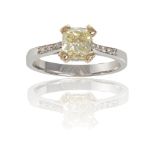 A FANCY COLOURED DIAMOND AND DIAMOND RINGCentering a fancy yellow diamond weighing 1.28cts, within a