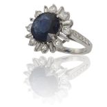 A SAPPHIRE AND DIAMOND CLUSTER RINGThe round-cut sapphire weighing 5.22cts, in a four-claw