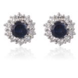 A PAIR OF SAPPHIRE AND DIAMOND CLUSTER EARSTUDSEach set centrally with a round-shaped sapphire,