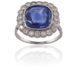 A SAPPHIRE AND DIAMOND CLUSTER RINGThe cushion-shaped sapphire, weighing approximately 4.70cts,