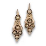 Pendientes largos populares s.XIX con flores con diamantes y volutas. En oro de 18K. Longitud:5 cms.