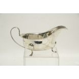 An oval sauce boat with cut-card rim, loop handle, & on three pad feet, 6¾" long; London 1934, by