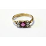 An 18ct gold ring set round-cut ruby flanked by a pair of diamonds either side.