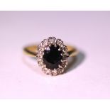 An 18ct gold ring set oval sapphire within a border of small diamonds.