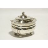 A regency-style tea caddy of squat oval form, with gadrooned rim, hinged lid, & on four ball feet,