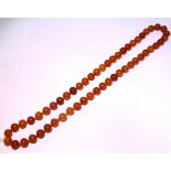 An amber necklace, the opaque round beads of varying colour; & an amber chip necklace of graduated