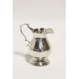 A George II baluster-shaped cream jug with card-cut rim, scroll handle, & on round pedestal foot,