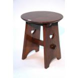 An Arts & Crafts oak low occasional table with circular top, on shaped supports with pierced heart
