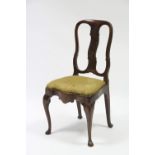 An early 18th century elm dining chair with waved splat to the open back, having padded drop-in seat