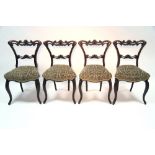 A set of four William IV rosewood dining chairs with carved & pierced open backs, padded seats, & on