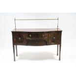 A Sheraton style mahogany serpentine-front sideboard with brass rail to the back, fitted central