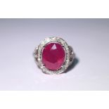 A ruby ring, the oval stone measuring approx. 12mm x 10mm, set within a border of small diamonds