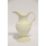 A Leeds-type creamware ovoid jug with part-reeded body & pedestal foot, interlaced reeded strap