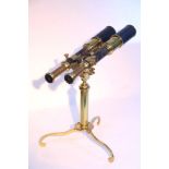 A VICTORIAN BRASS BINOCULAR TELESCOPE with leather-covered tubes, and on triform stand, 13¾" long.