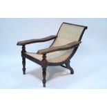 An eastern hardwood ‘plantation’ chair with extendable arms, woven cane seat & back, on turned legs;