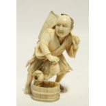 A Japanese carved ivory okimono of a fisherman with his scoop net over his shoulder, a bucket of