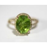 A PERIDOT & DIAMOND RING, the large oval centre stone measuring approx. 11mm & 8mm, within a