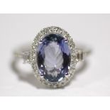 A TANZANITE & DIAMOND RING, the oval centre stone measuring approx. 11mm x 8mm, within a border of