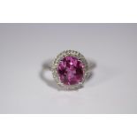 A PINK SAPPHIRE & DIAMOND RING, the oval centre stone measuring approx. 10mm x 9mm, within a