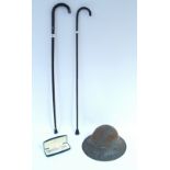 Two gent’s walking canes, one with silver mounts; together with a steel safety helmet & a Cross