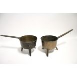 Two early cast brass saucepans, each with tripod base.