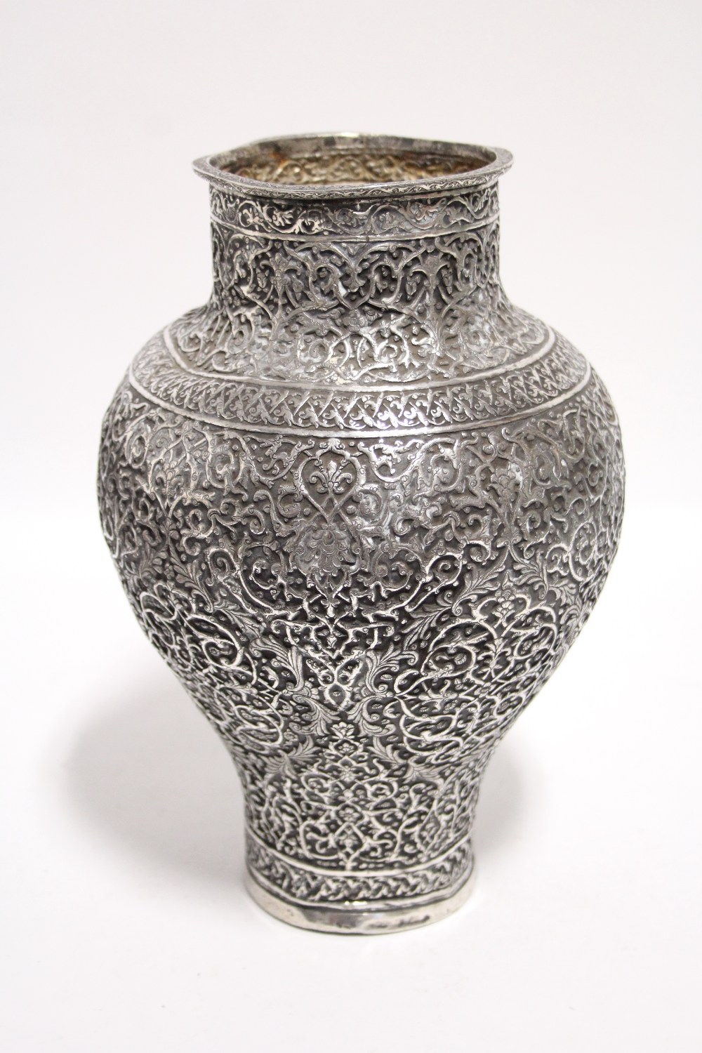AN INDIAN SILVER VASE of ovoid form with narrow neck & foot, with all-over finely embossed &