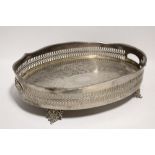A large oval two-handled tray with pierced waved gallery, on four foliate-scroll handles; 21" x