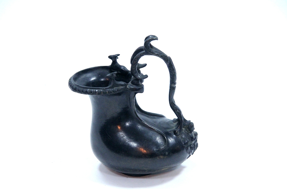 A bronze ewer in the form of a Pompeian Ascos; 7".