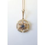 An un-marked yellow metal openwork circular pendant set central sapphire within borders of seed