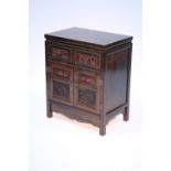 A Chinese hardwood dwarf cabinet fitted two frieze drawers above a pair of panel doors, all with